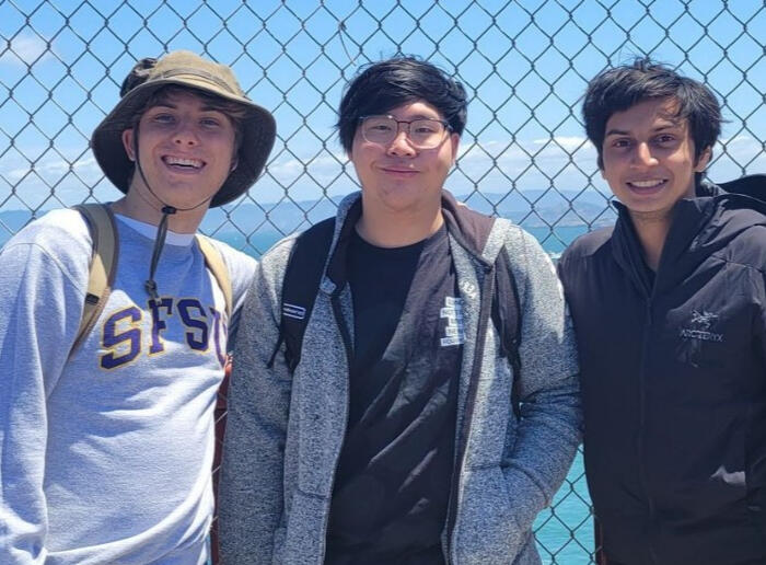 Three people on the Golden Gate Bridge smiling.